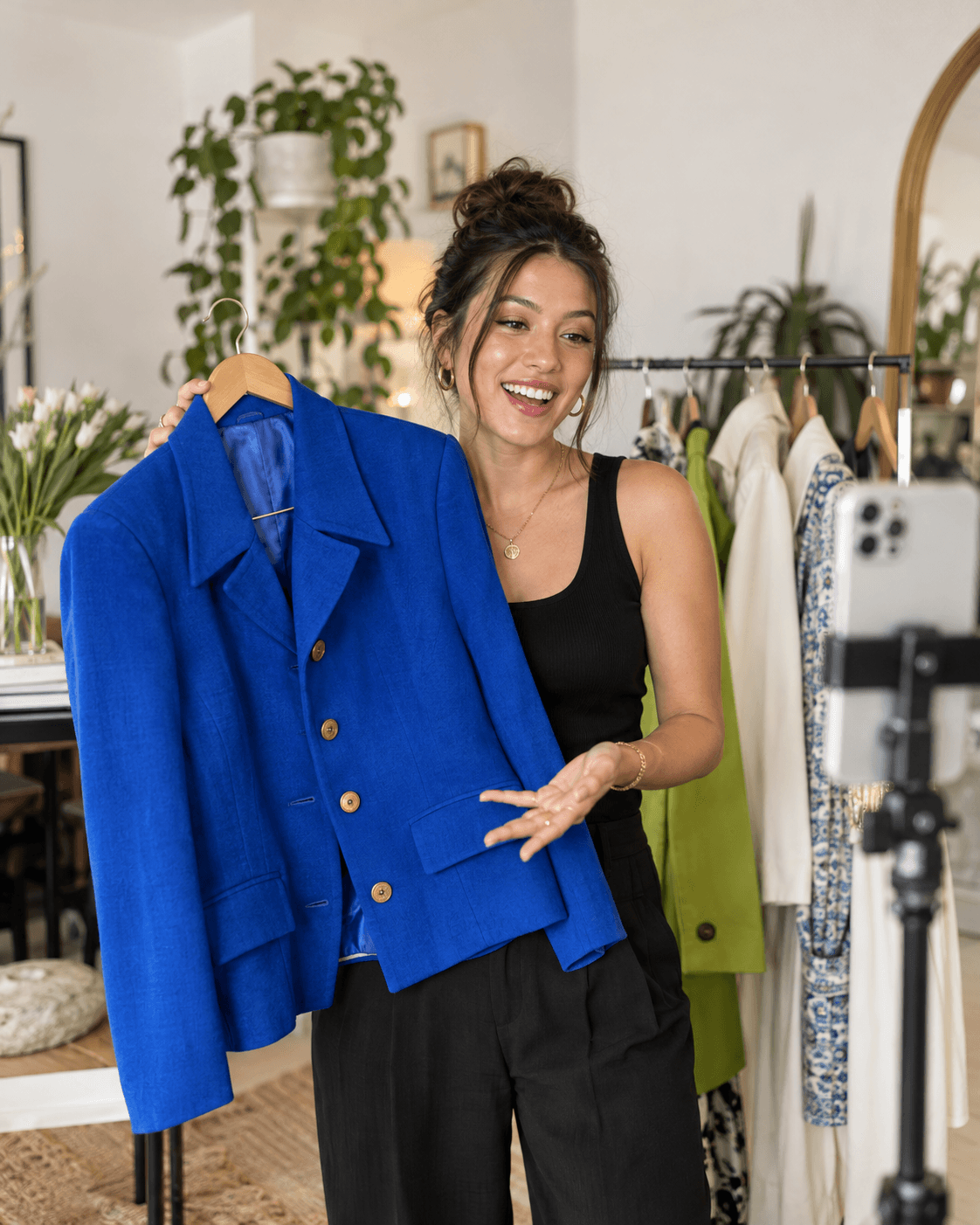 Eine Modeverkäuferin präsentiert eine blaue Jacke vor einer Livestream-Kamera