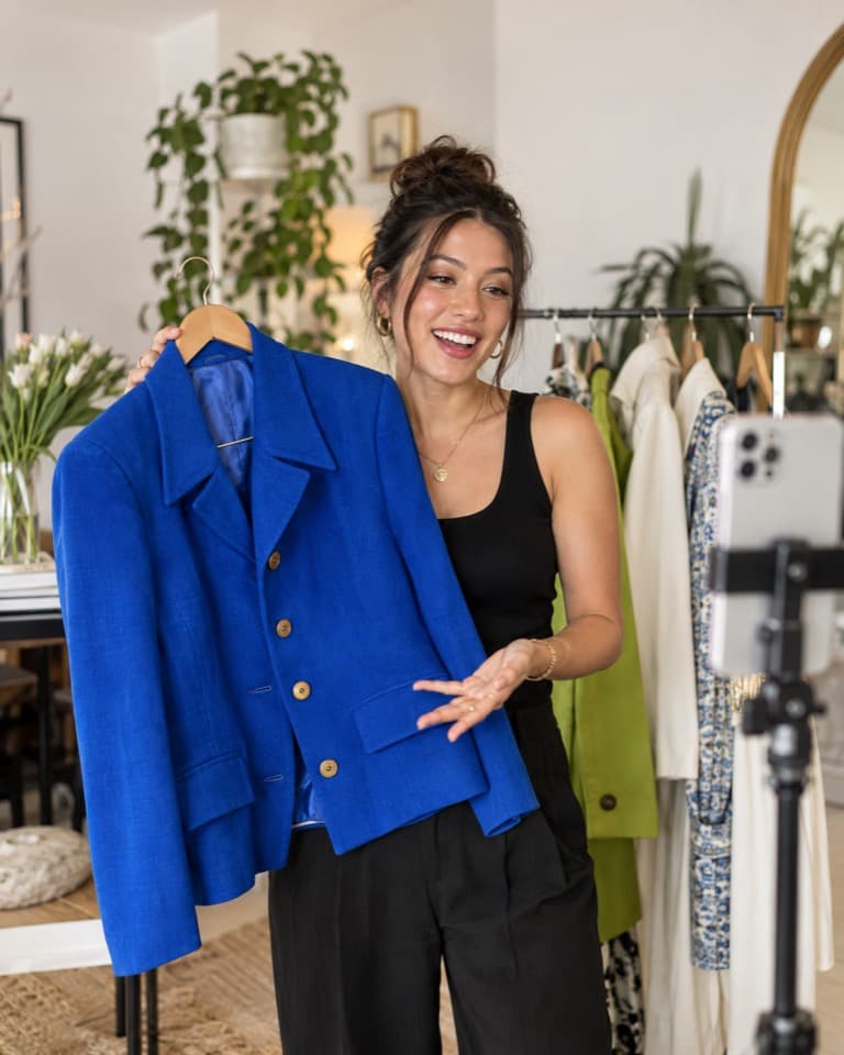 Eine Host präsentiert eine blaue Vintage-Jacke vor einer Livestream-Kamera